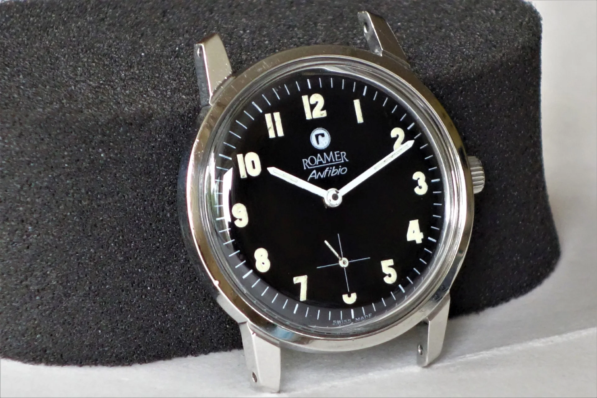 Schwarze Armbanduhr mit silberfarbenem Gehäuse und Leuchtziffern.