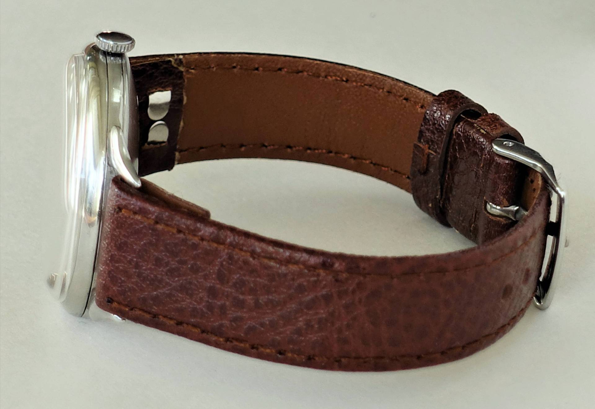 Armbanduhr mit braunem Lederarmband und silberfarbenem Gehäuse.