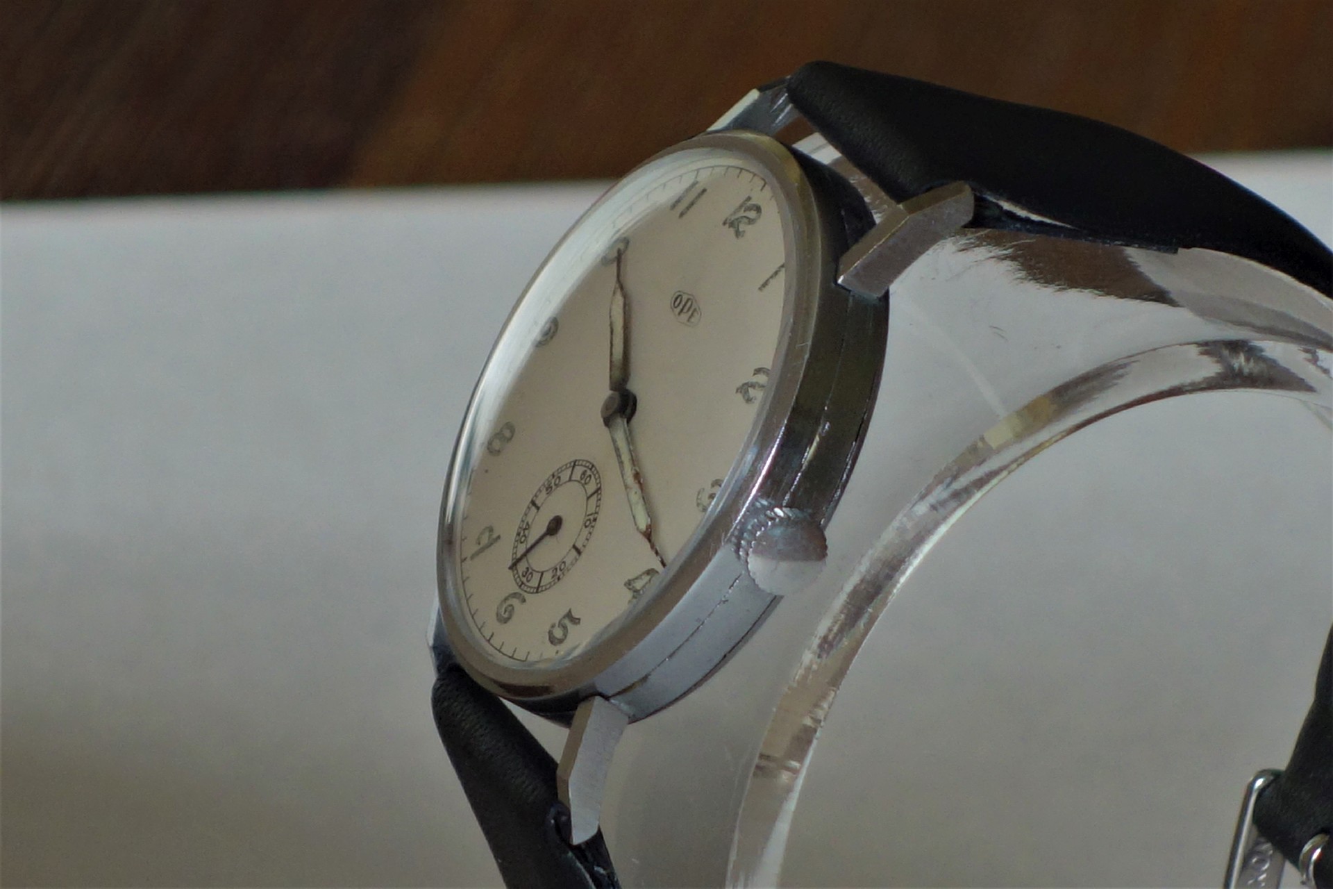 Silberfarbene mechanische Armbanduhr mit weißem Zifferblatt und schwarzem Armband.