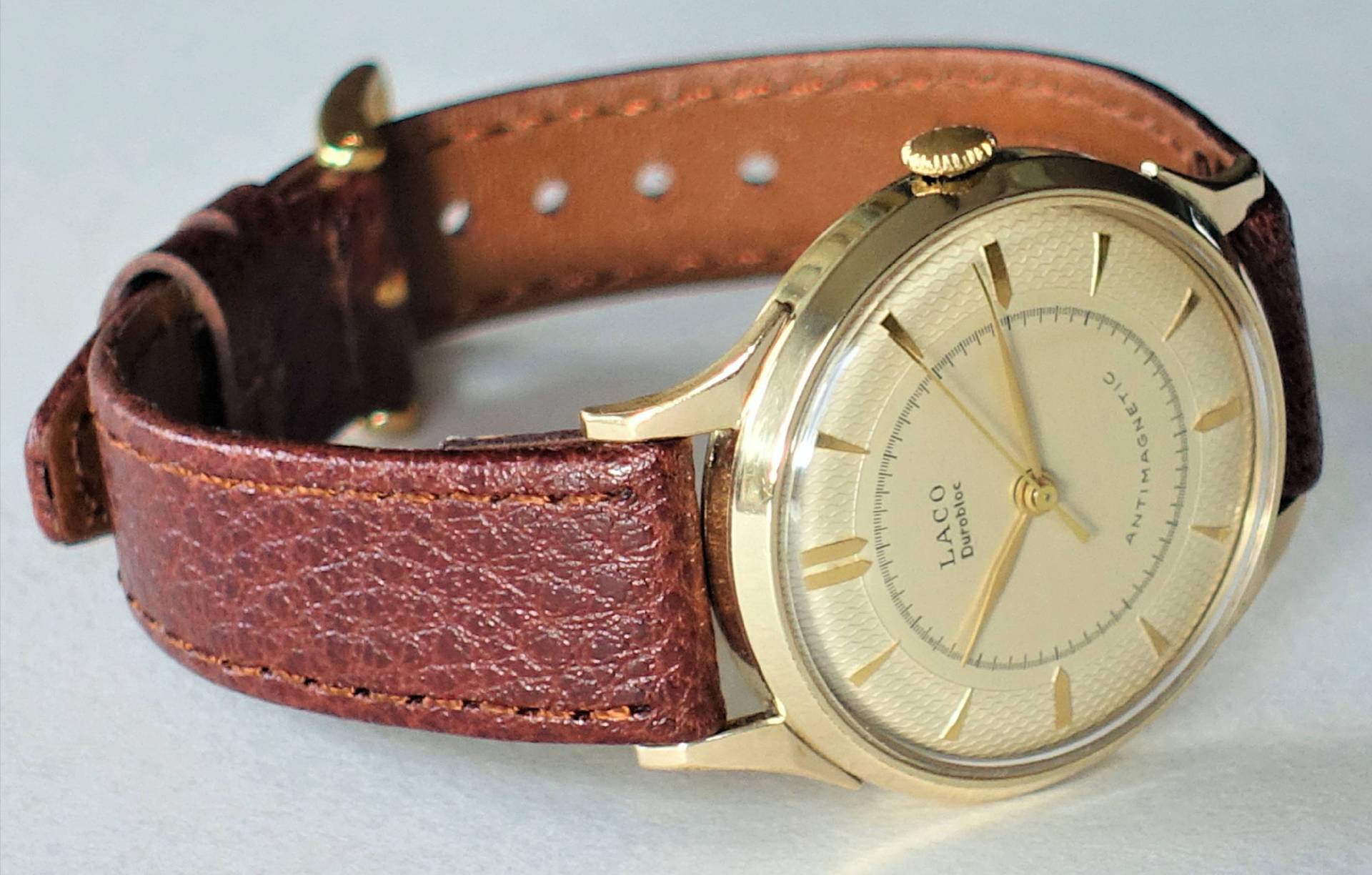 Analoge Armbanduhr mit goldfarbenem Gehäuse und braunem Lederarmband.