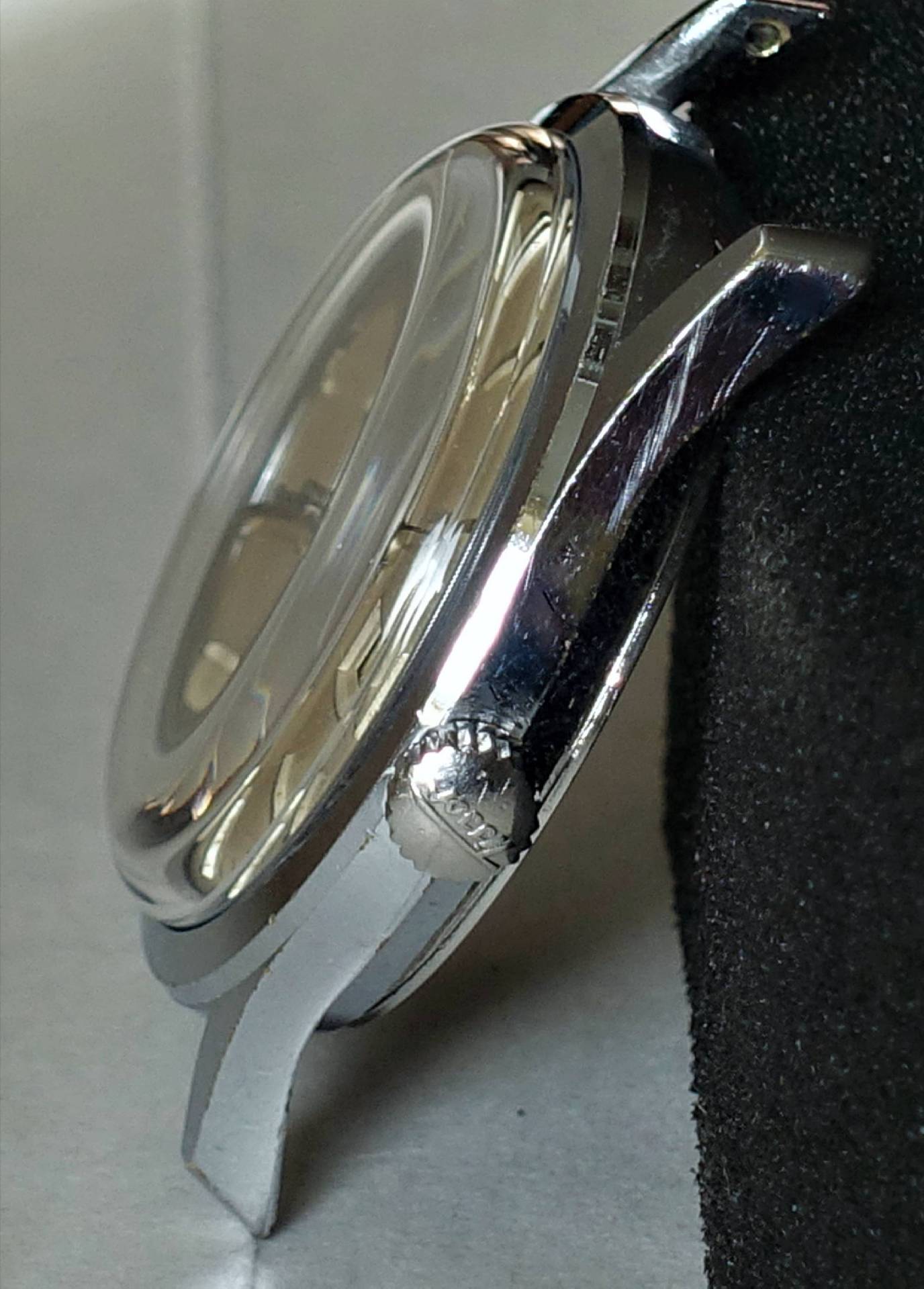 Silberfarbenes Uhrgehäuse mit seitlicher Krone und gewölbtem Glas.