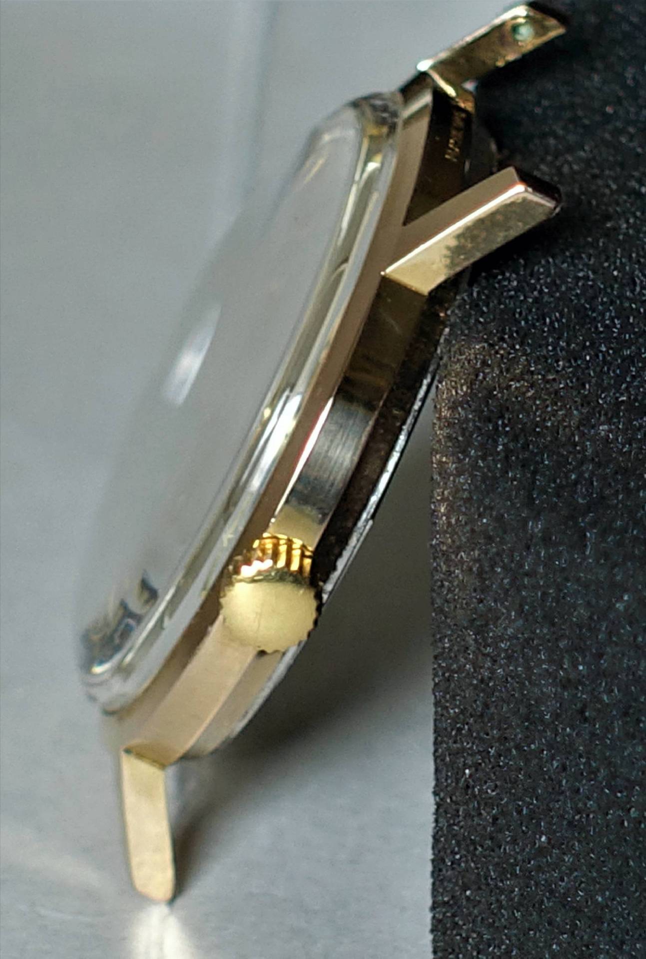 Flaches, goldfarbenes Uhrengehäuse mit seitlicher Krone.