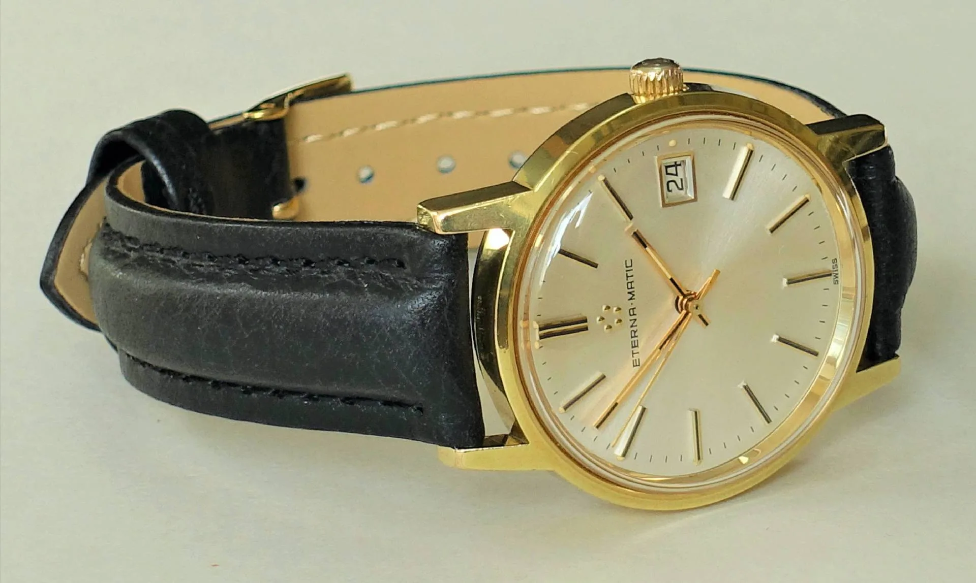 Armbanduhr goldfarben schwarz Goldfarbene Armbanduhr mit schwarzem Lederarmband und hellem Zifferblatt.