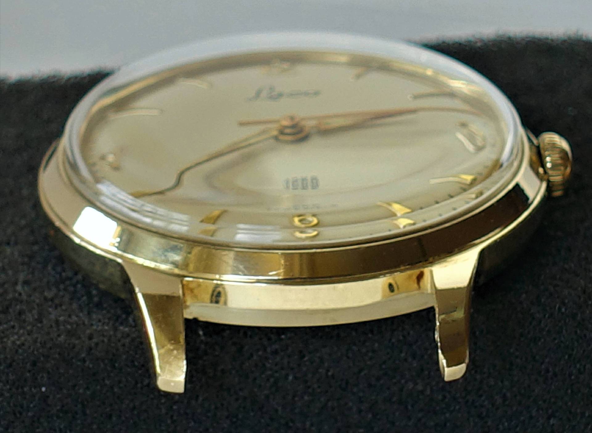 Goldfarbene Armbanduhr mit hellem Zifferblatt und goldenen Zeigern.