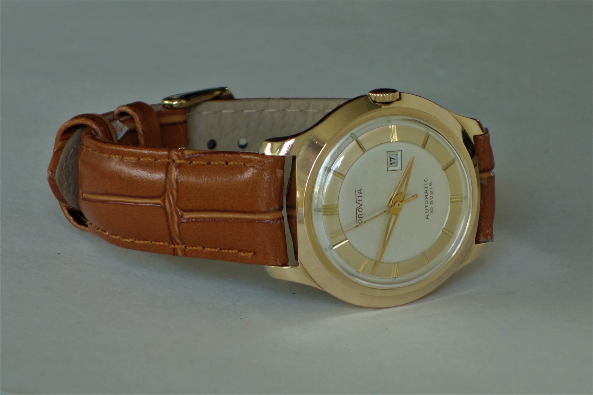 Armbanduhr mit braunem Armband und hellem Zifferblatt.