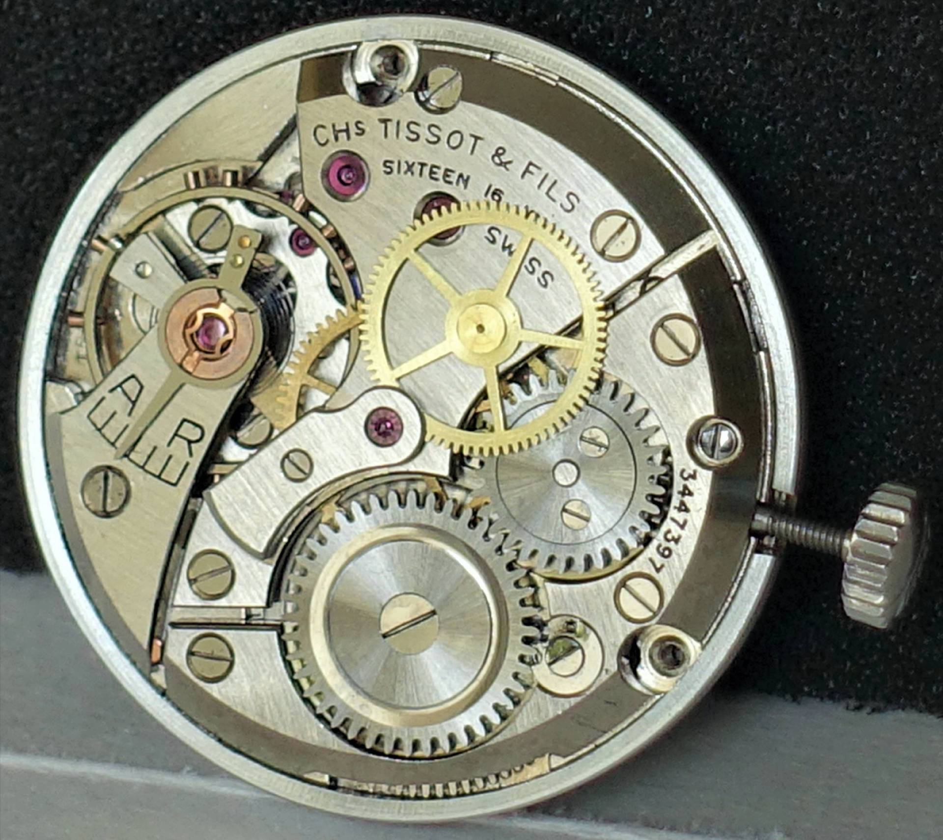 Mechanisches Uhrwerk von Tissot mit sichtbaren Zahnrädern und Aufzugswelle in silberner und goldfarbener Ausführung.