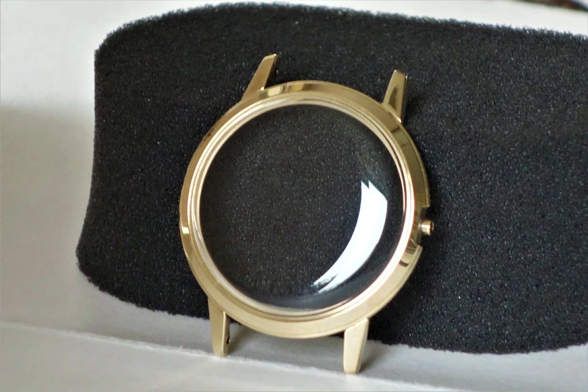 Rundes Uhrengehäuse in goldfarbener Optik mit transparentem Uhrglas.