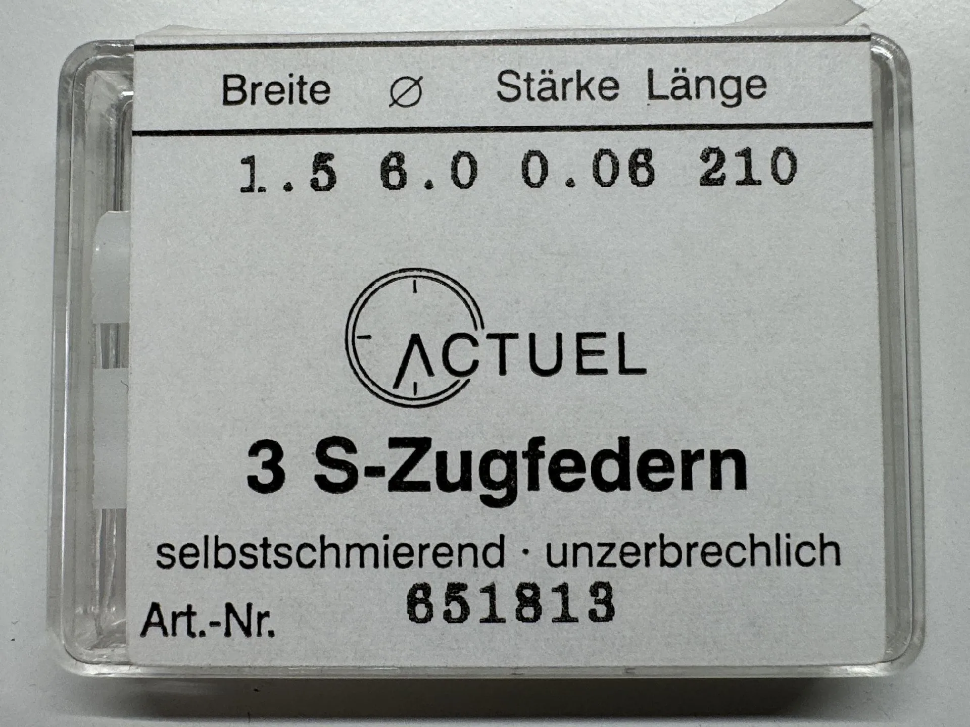 Drei silberfarbene Zugfedern für Uhren in transparenter Verpackung.