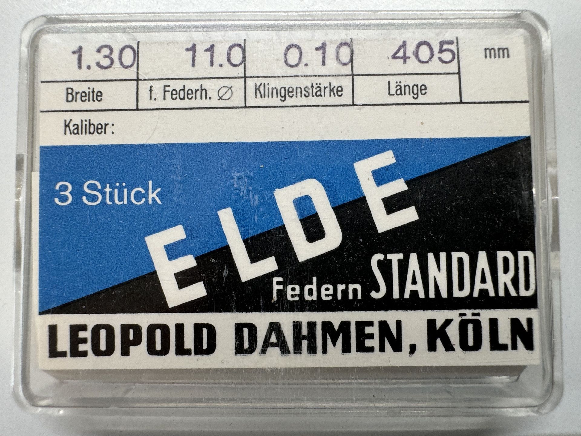 Verpackung mit drei Aufzugsfedern für Uhrwerke, beschriftet mit technischen Angaben und Herstellername.