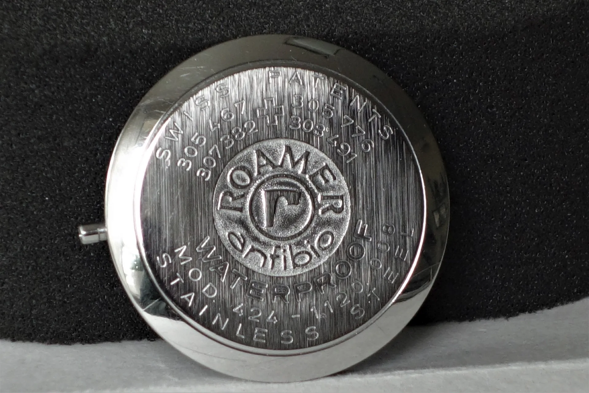 Roamer Uhrenboden silberfarben Runder silberfarbener Uhrenboden mit eingeprägtem Roamer-Logo und Schriftzug.