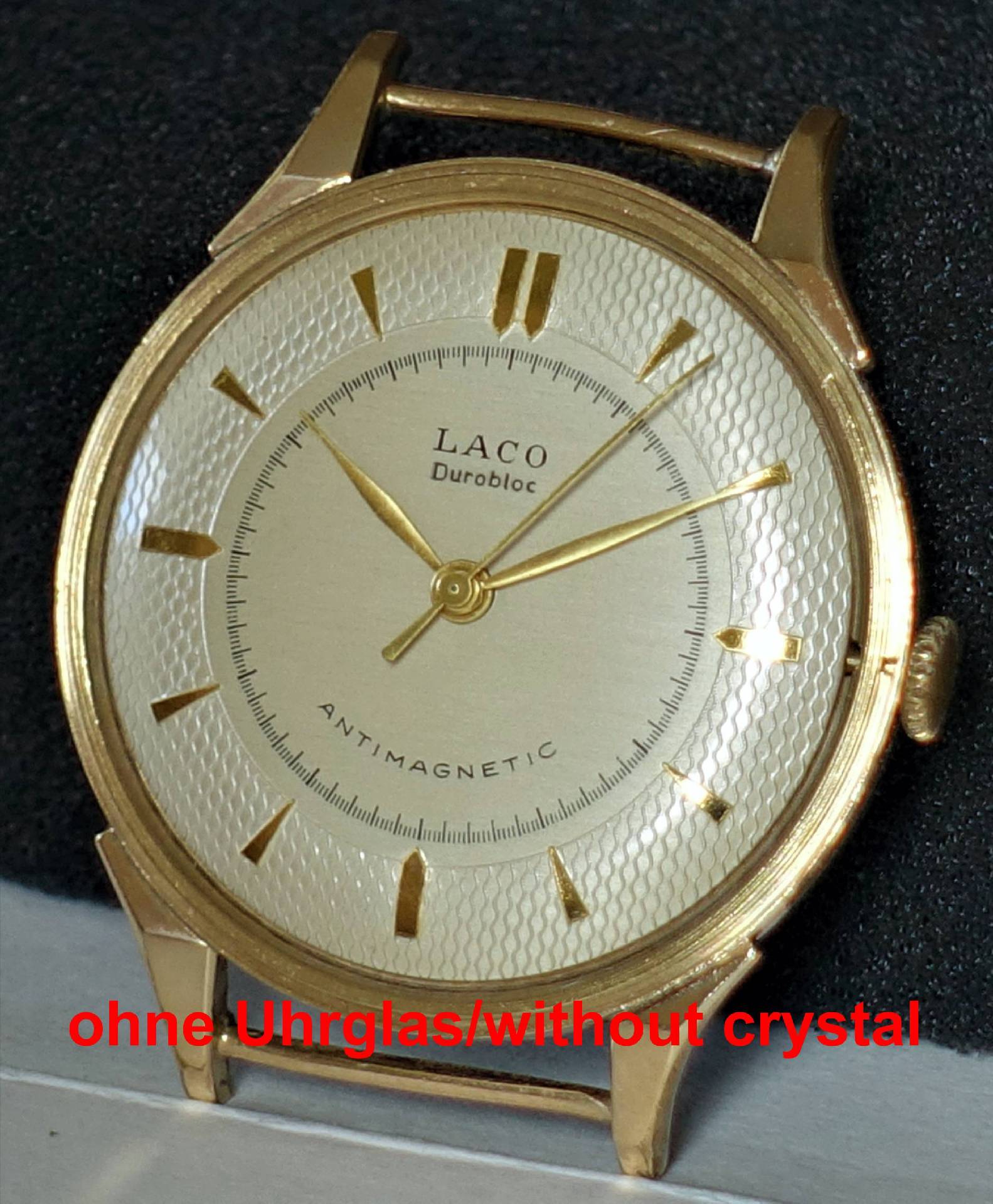 Goldfarbene Armbanduhr ohne Uhrglas mit hellem Zifferblatt und goldfarbenen Zeigern.