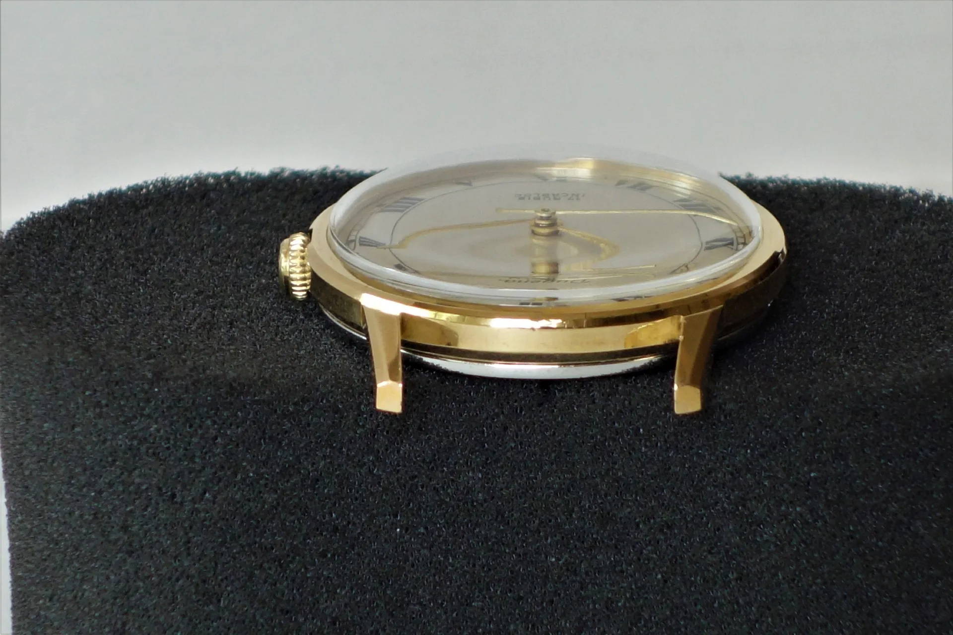 Rundes Uhrgehäuse in goldfarbener Optik mit aufgesetztem Glas und seitlicher Krone.