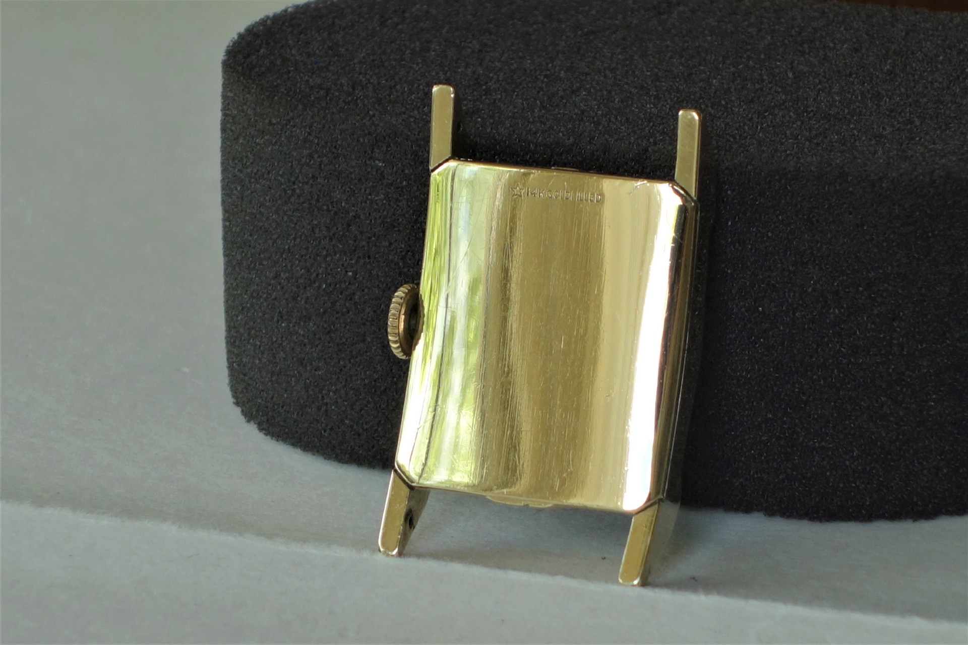 Rechteckiges Uhrengehäuse in goldfarbener Ausführung mit seitlicher Krone.