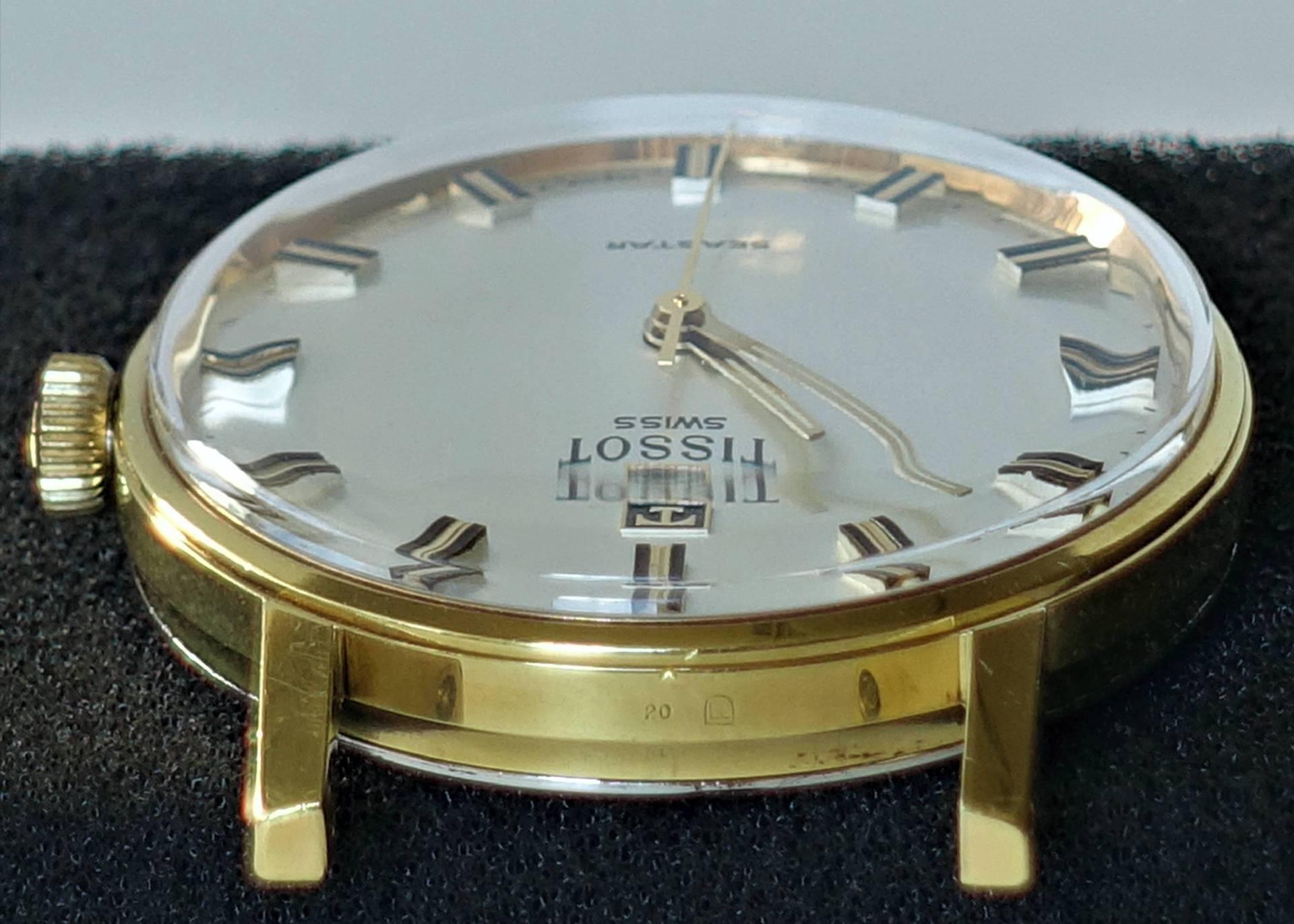 Goldfarbene Armbanduhr mit hellem Zifferblatt und aufgesetzten Indizes.