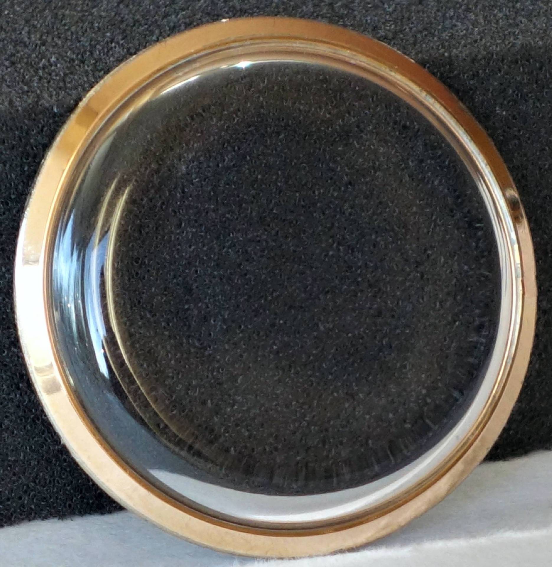 Transparentes Uhrglas mit einem goldfarbenen Rand.