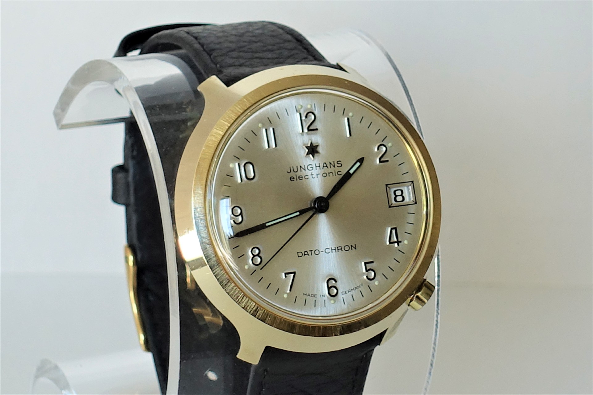 Analoge Armbanduhr mit hellem Zifferblatt, goldfarbenem Gehäuse und schwarzem Armband.