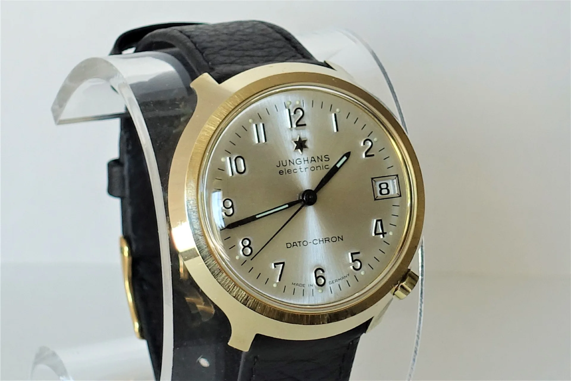Analoge Armbanduhr mit hellem Zifferblatt, goldfarbenem Gehäuse und schwarzem Armband.