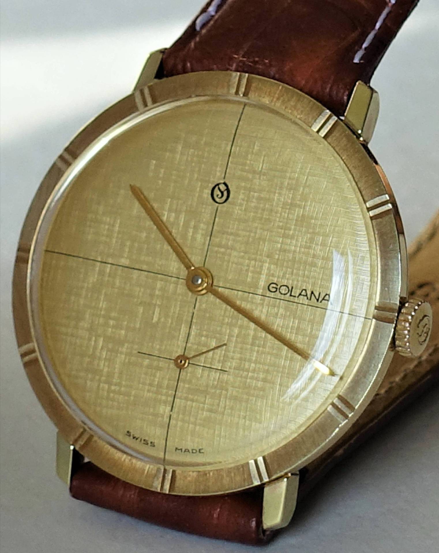 Goldfarbene Armbanduhr mit braunem Lederarmband und schlichtem Zifferblatt.