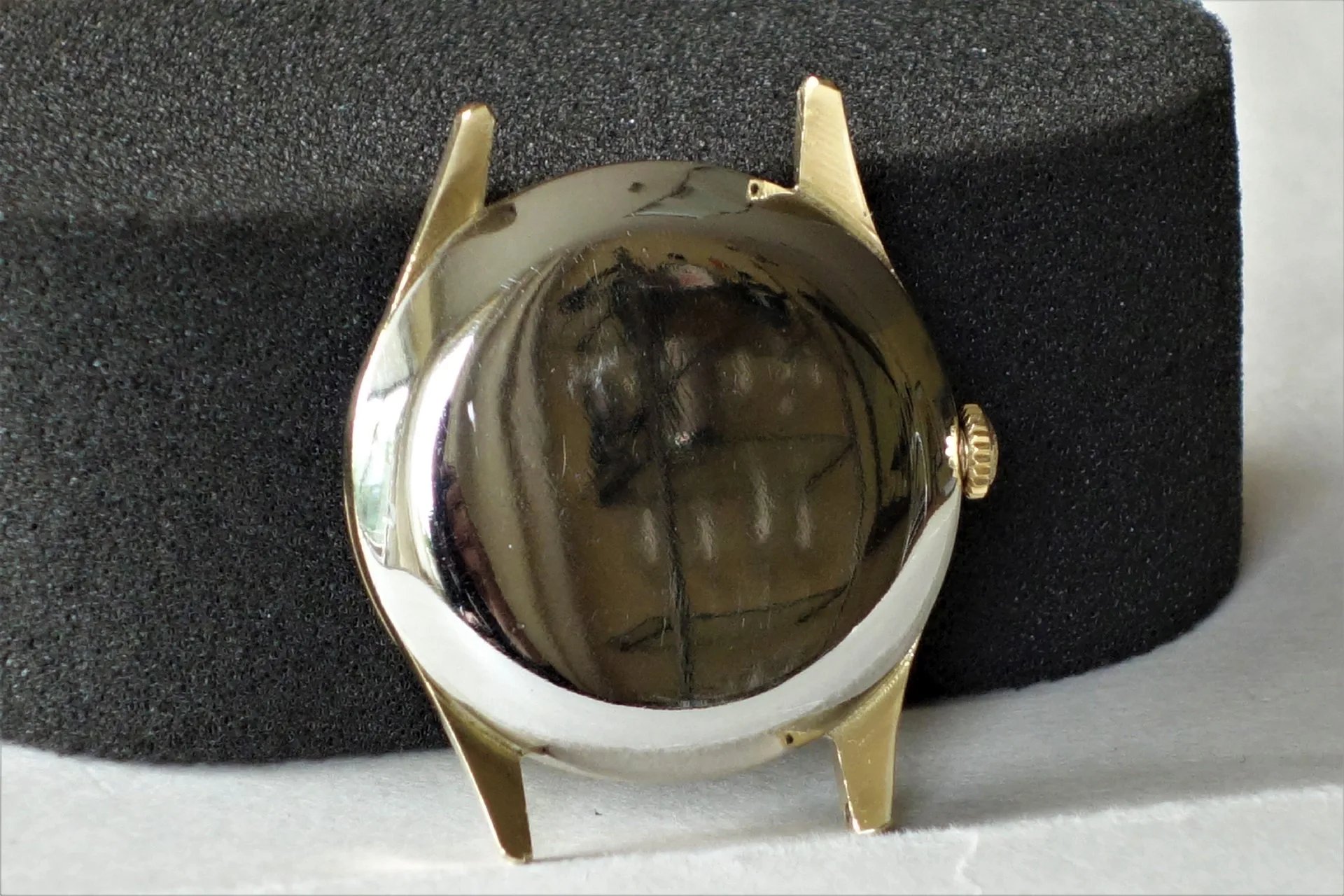 Rundes Uhrengehäuse in goldfarbener Optik mit aufgesetztem Gehäuseboden.