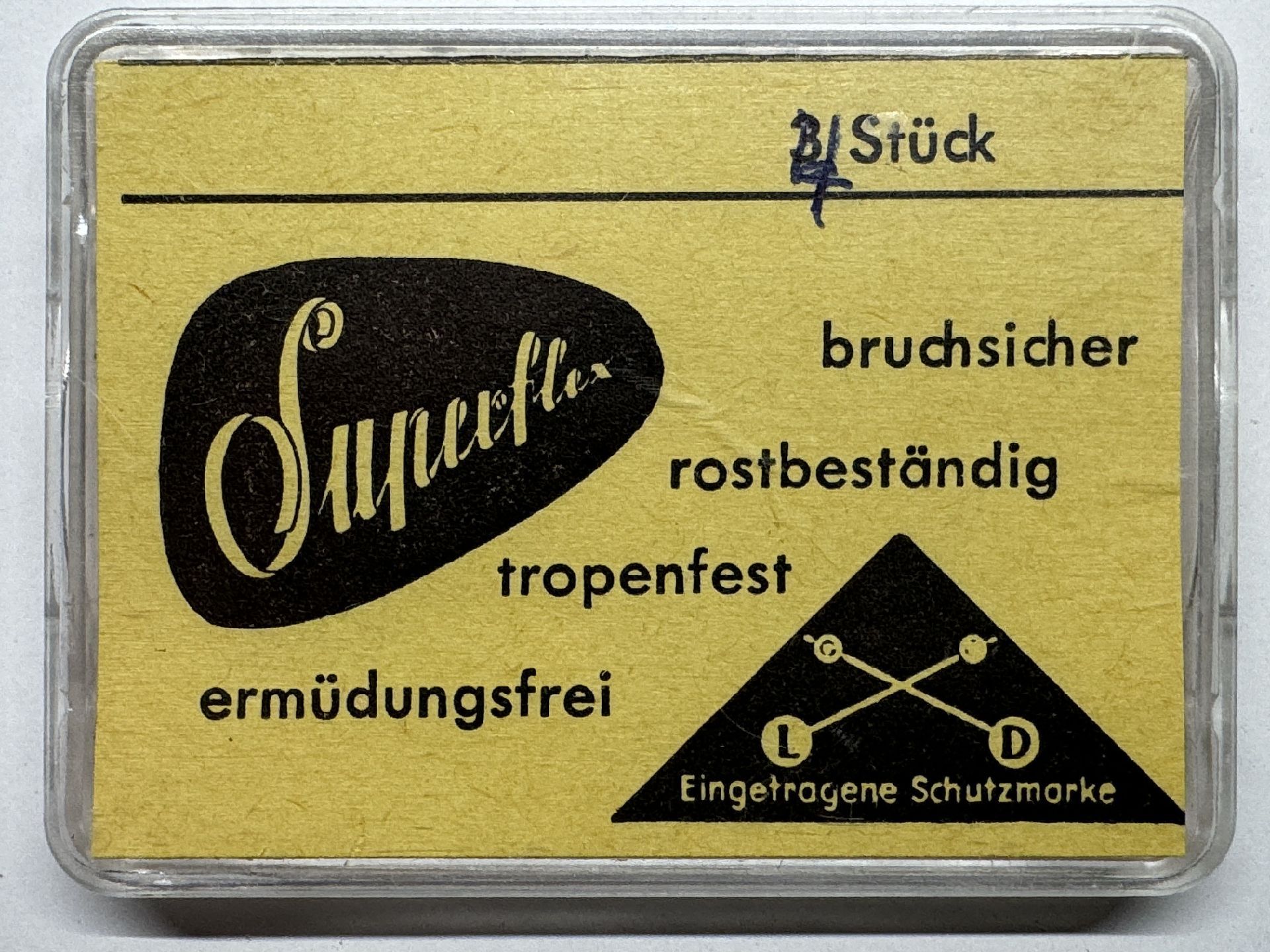 Gelbe Verpackung mit der Aufschrift "Superflex" für eine bruchsichere und rostbeständige Uhrmacherfeder.