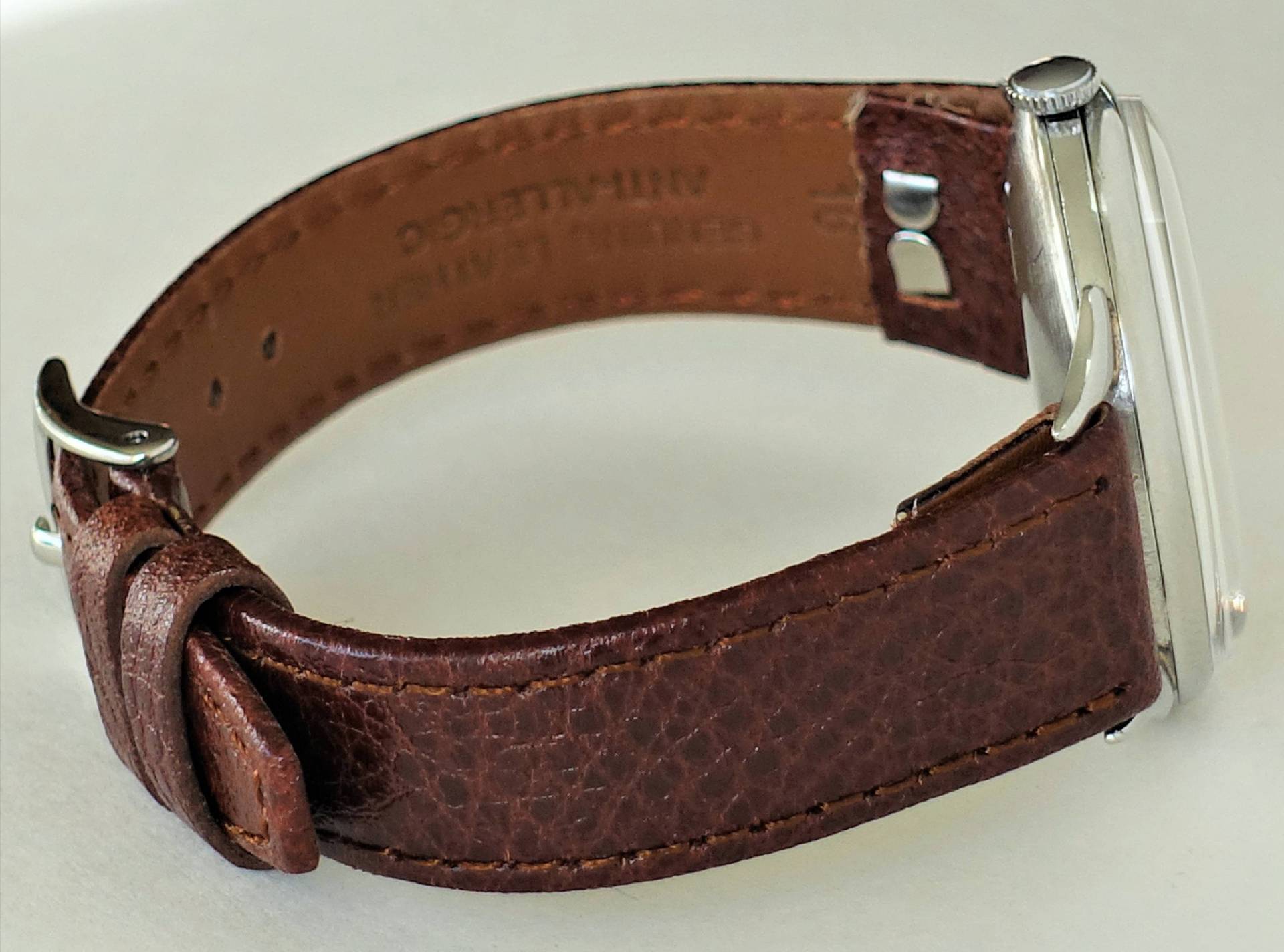Armbanduhr mit braunem Lederarmband und silberfarbenem Gehäuse.