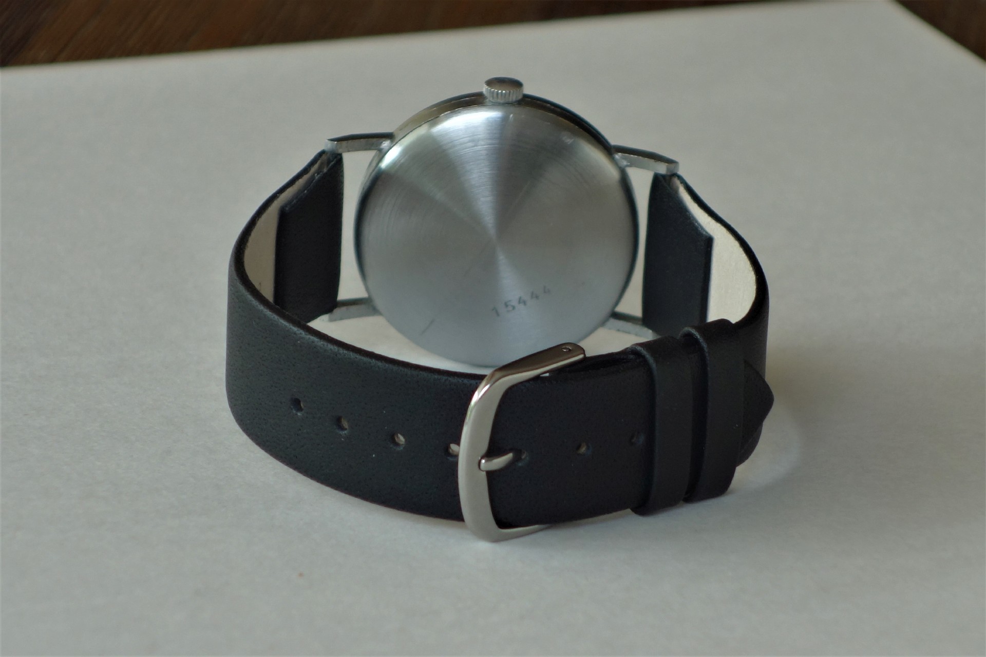 Armbanduhr mit schwarzem Armband und silberfarbener Rückseite.