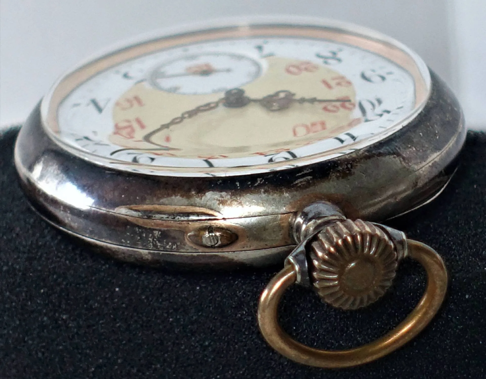 Silberfarbene Taschenuhr mit weißem Zifferblatt und goldfarbener Krone.