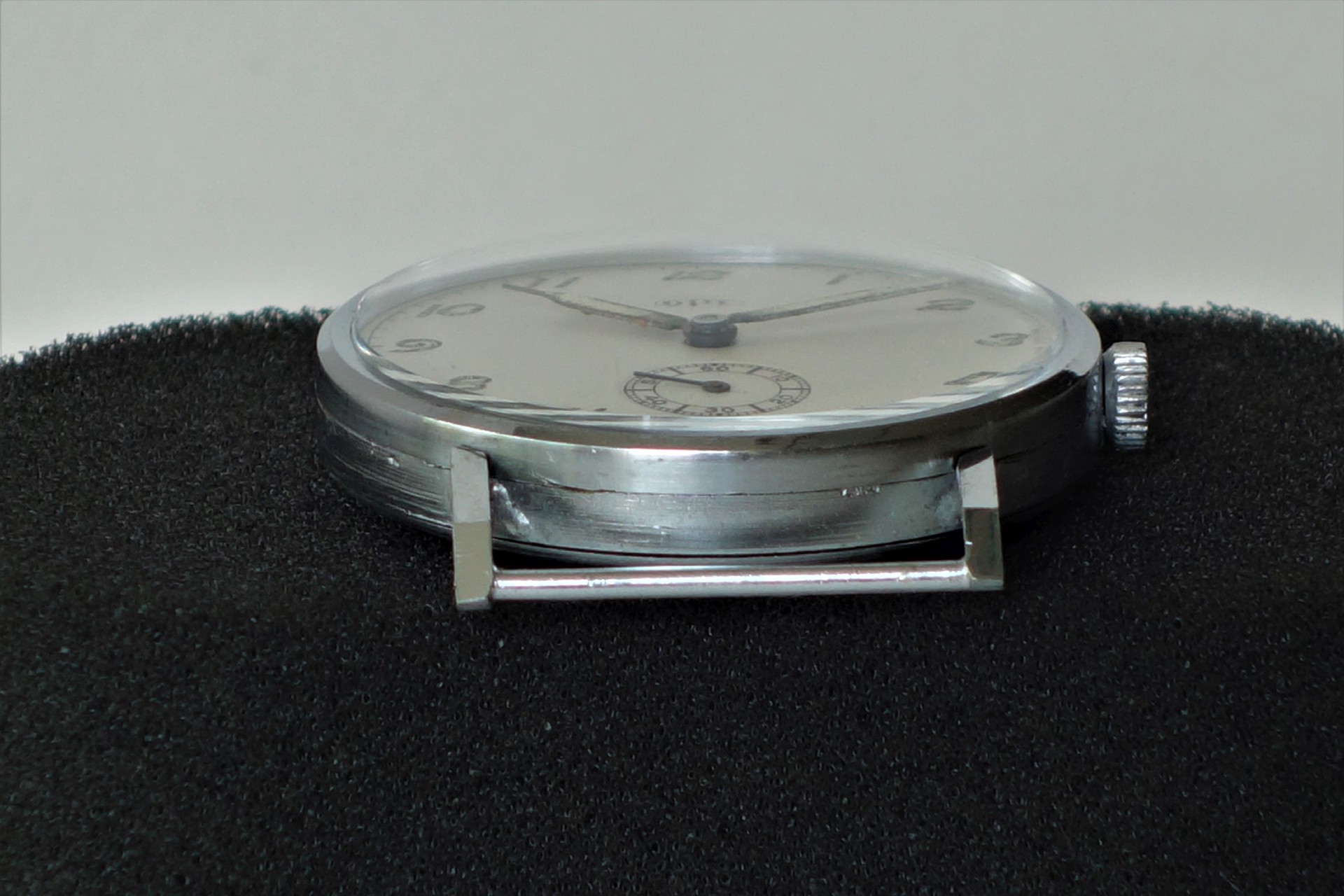 Flache silberfarbene mechanische Armbanduhr mit weißem Zifferblatt und kleiner Sekunde.