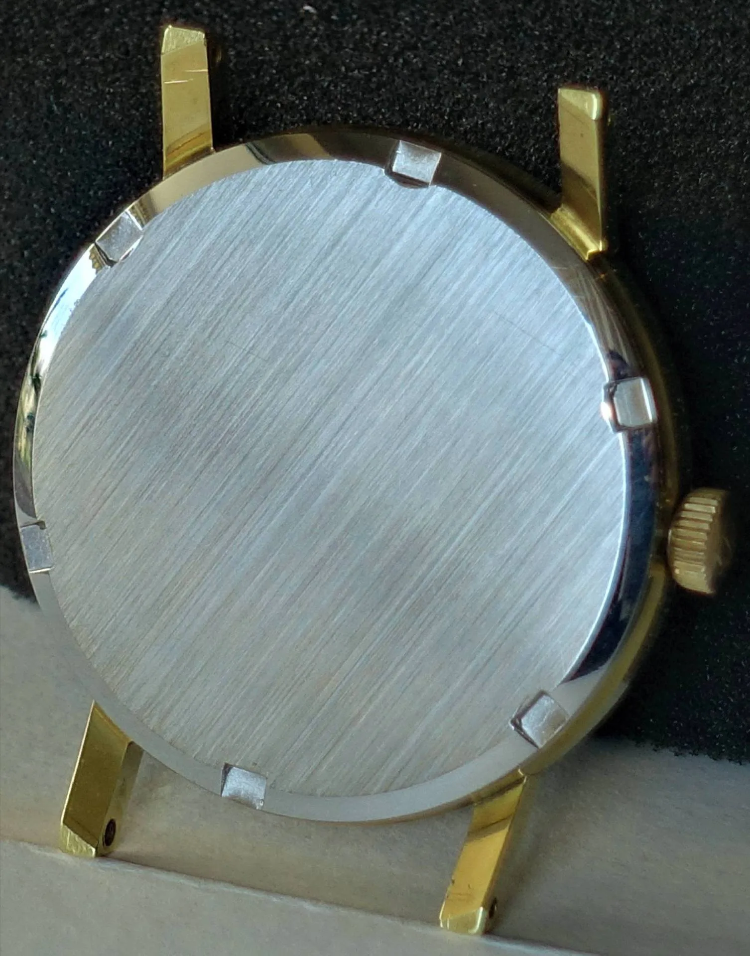 Gehäuse goldfarben silberfarben Rundes Uhrgehäuse mit goldfarbenen Hörnern und silberfarbener Rückseite.