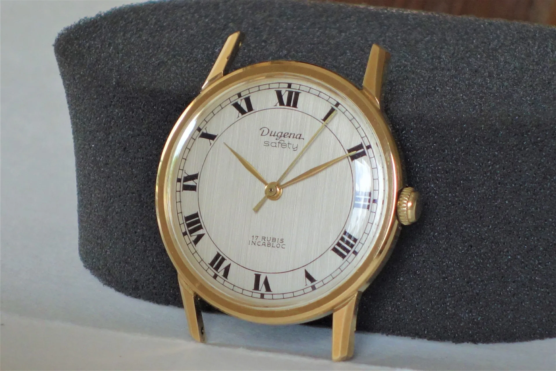 Dugena Armbanduhr goldfarben Runde Armbanduhr mit goldfarbenem Gehäuse und weißem Zifferblatt mit römischen Zahlen.