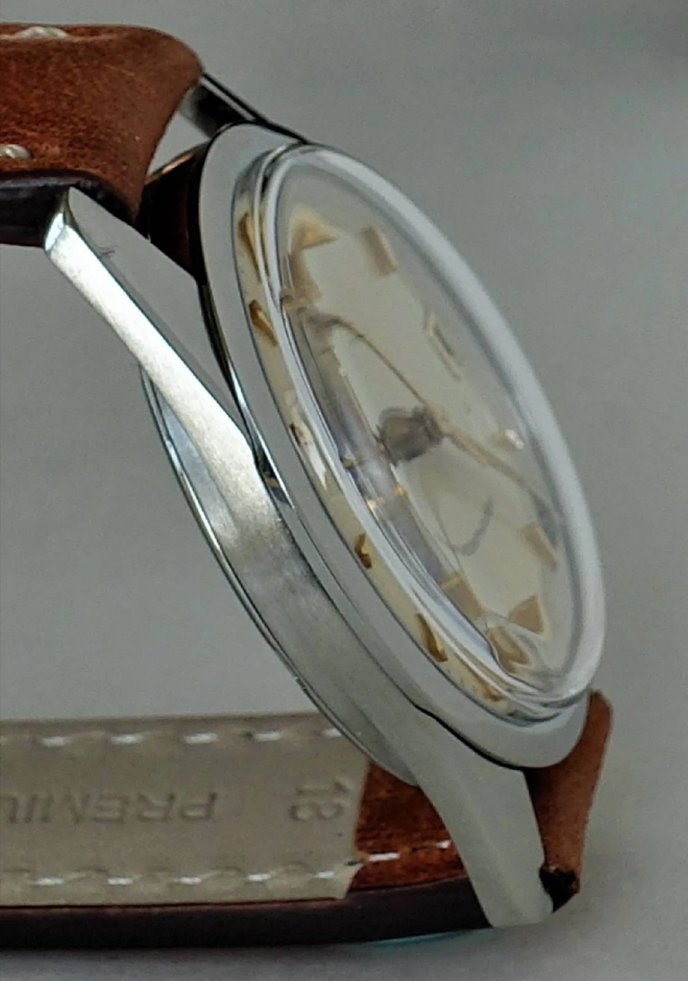Silberfarbene Armbanduhr mit braunem Lederarmband und hellem Zifferblatt.
