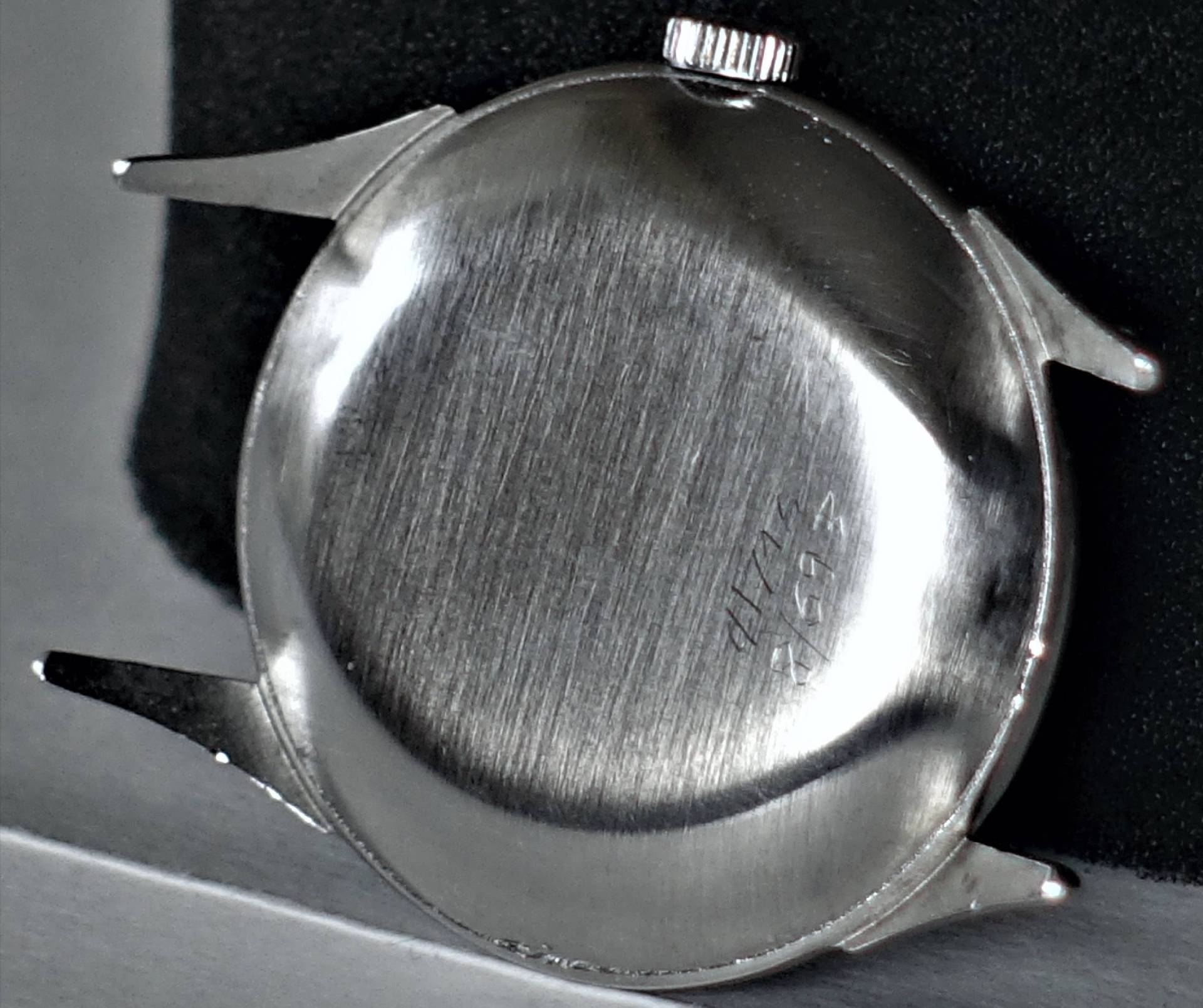 Rückseite eines silberfarbenen Uhrgehäuses mit sichtbarer Gravur und ohne montiertes Armband.