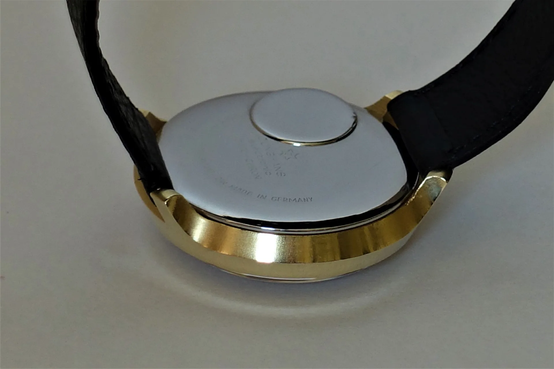 Uhrenboden silberfarben Silberfarbener Uhrenboden mit goldfarbenem Gehäuserand und schwarzem Armband.