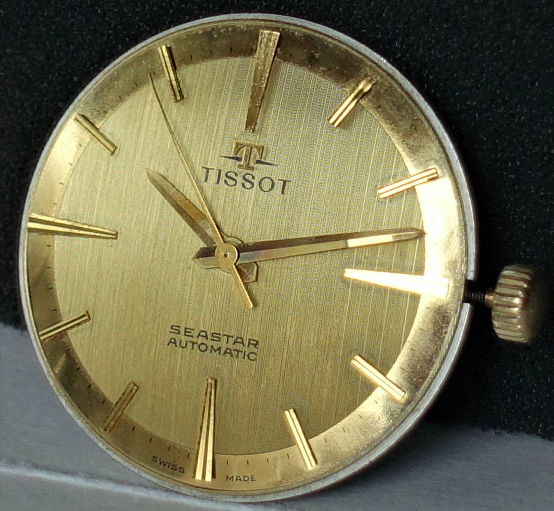 Goldenes Zifferblatt einer Tissot Seastar Automatic Armbanduhr mit goldfarbenen Zeigern und Indizes.
