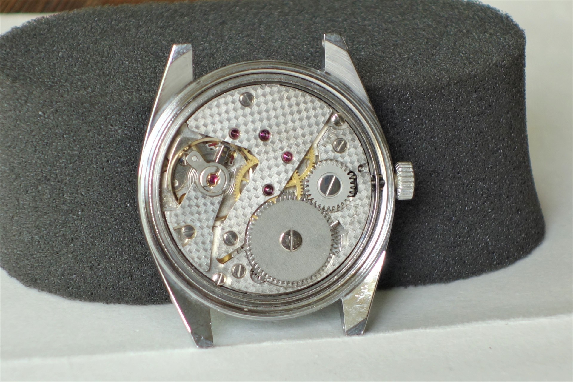 Mechanisches Uhrwerk in silberfarbenem Gehäuse ohne Zifferblatt und Zeiger.