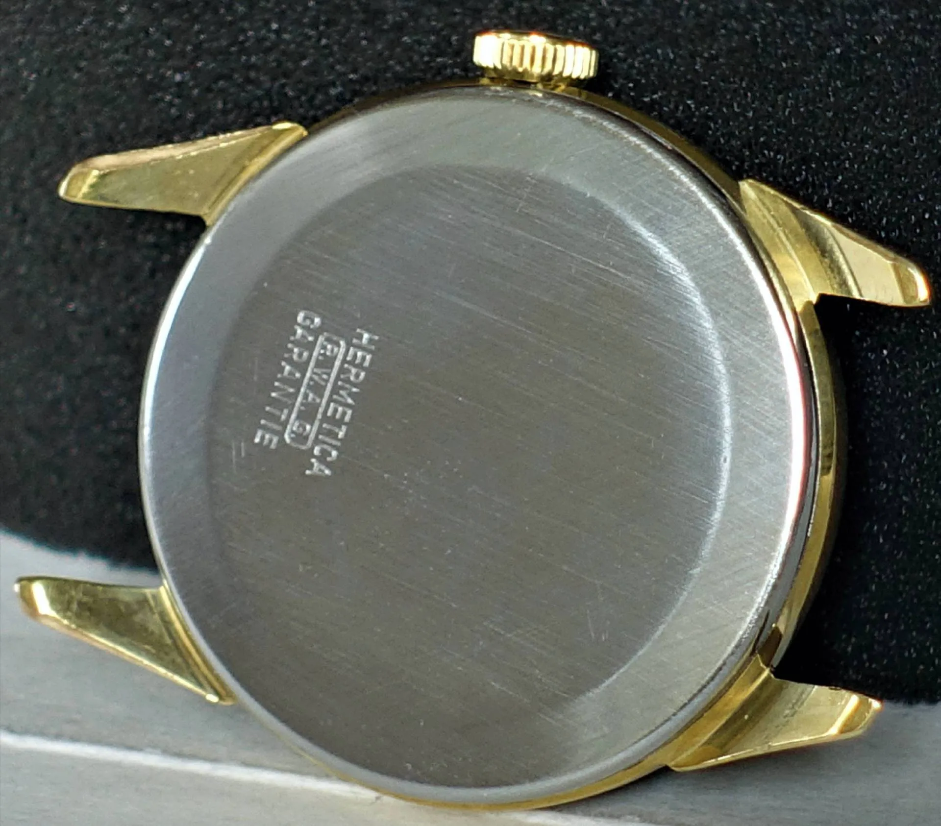Uhrgehäuse zweifarbig Rundes Uhrgehäuse mit silberfarbener Rückseite und goldfarbener Krone sowie goldfarbenen Bandanstößen.