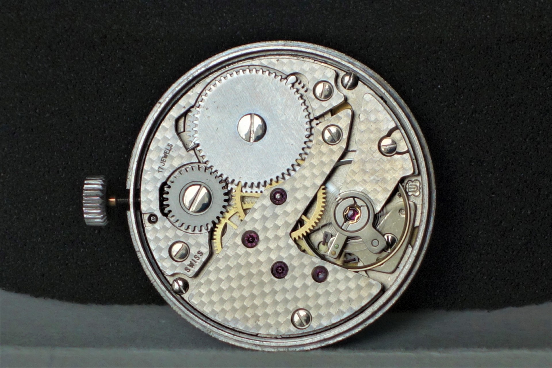 Mechanisches Uhrwerk in silberner Farbe mit sichtbaren Zahnrädern und Aufzugskrone.