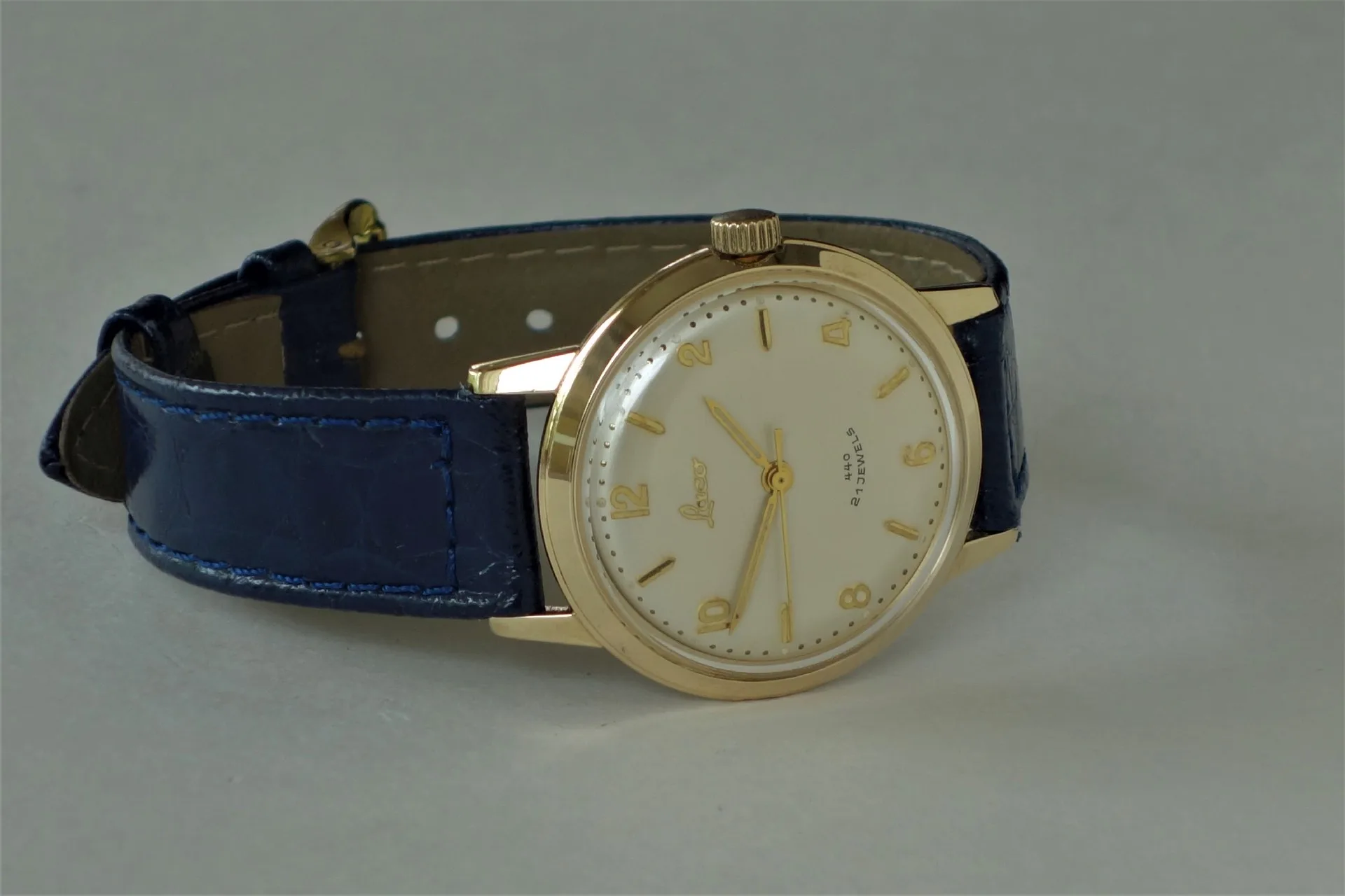 Analoge Armbanduhr mit goldfarbenem Gehäuse und blauem Armband.
