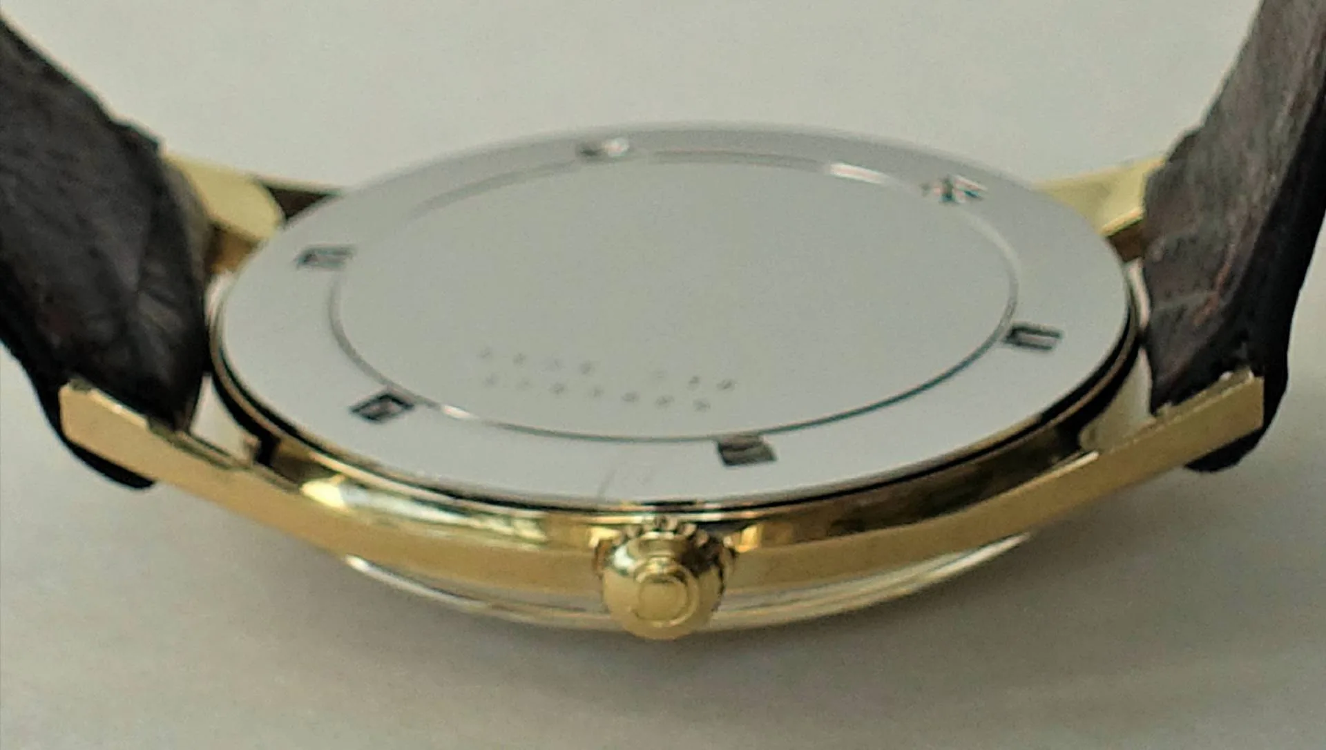 Uhrboden silberfarben Silberfarbener Boden einer Armbanduhr mit goldfarbenem Gehäuserand und schwarzem Armband.