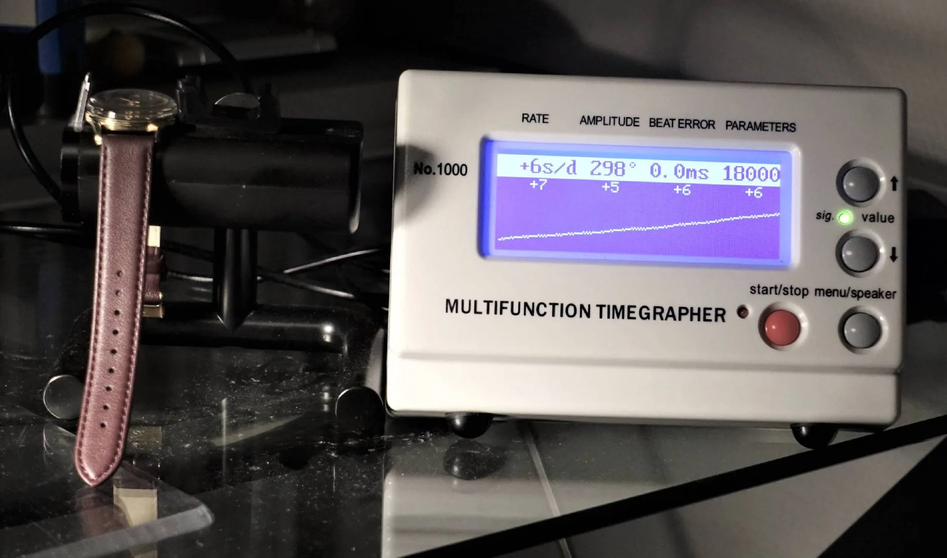 Weißes elektronisches Messgerät zur Analyse von mechanischen Uhren mit digitalem Display.