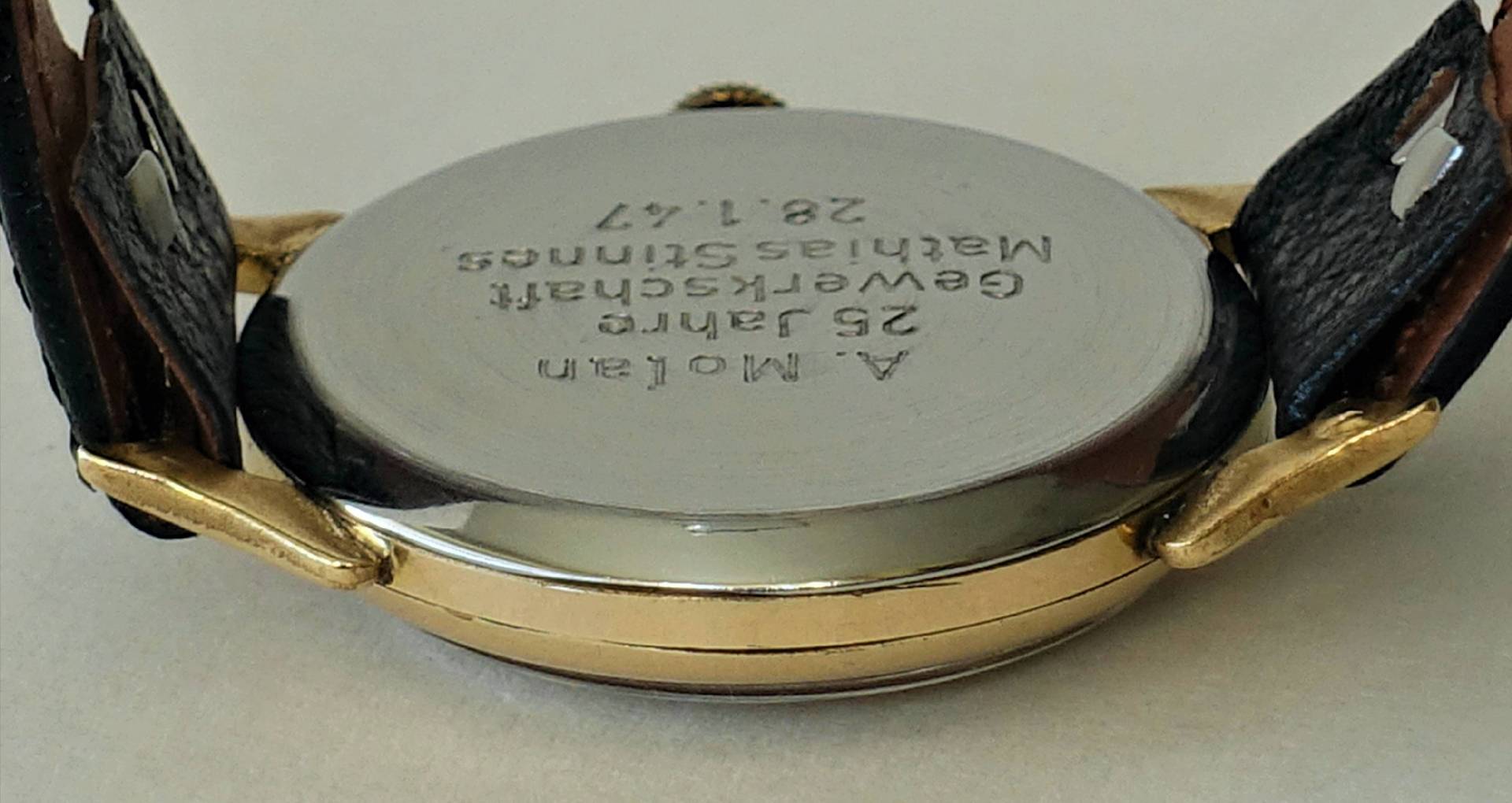 Silberfarbener Uhrboden mit Gravur an einer Armbanduhr mit schwarzem Armband.