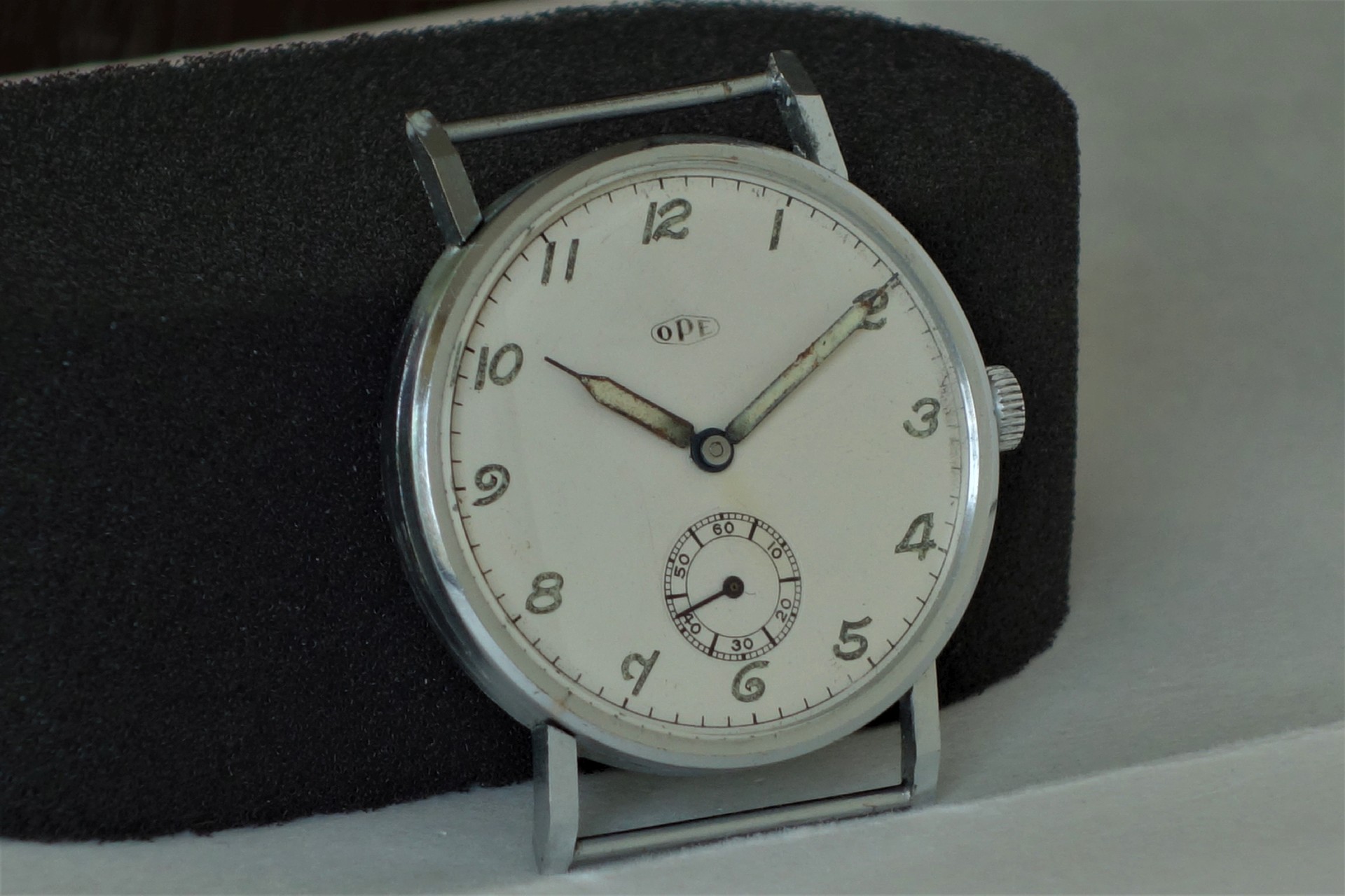 Runde silberfarbene Armbanduhr mit weißem Zifferblatt und kleiner Sekunde bei sechs Uhr.