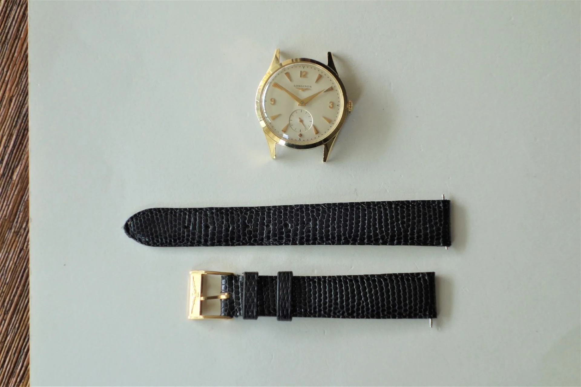 Uhrgehäuse goldfarben Rundes Uhrgehäuse in goldfarbener Optik mit hellem Zifferblatt und schwarzen Lederarmbandteilen.