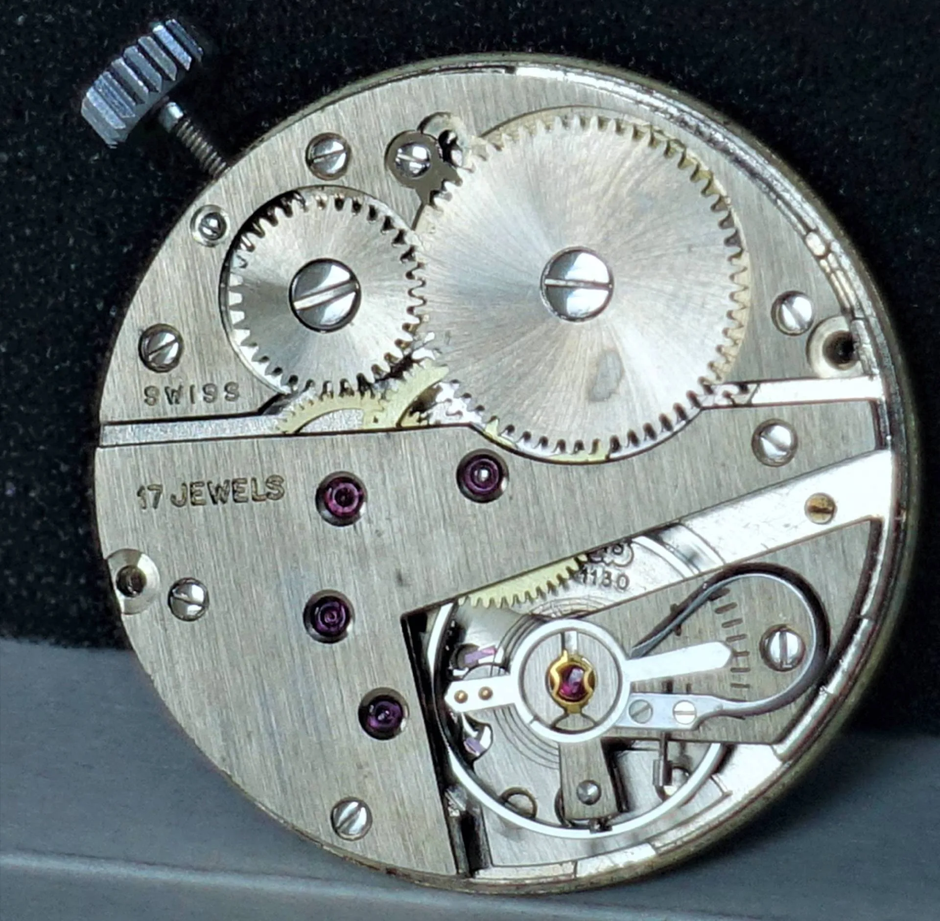 Mechanisches Uhrwerk aus silberfarbenem Metall mit sichtbaren Zahnrädern und 17 Lagersteinen.