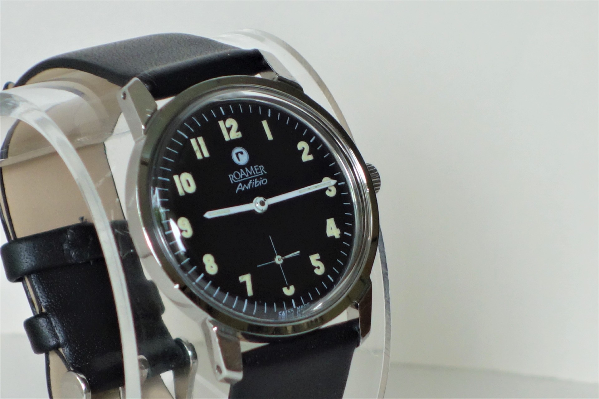 Schwarze Armbanduhr mit hellem Zifferblatt und schwarzem Armband.