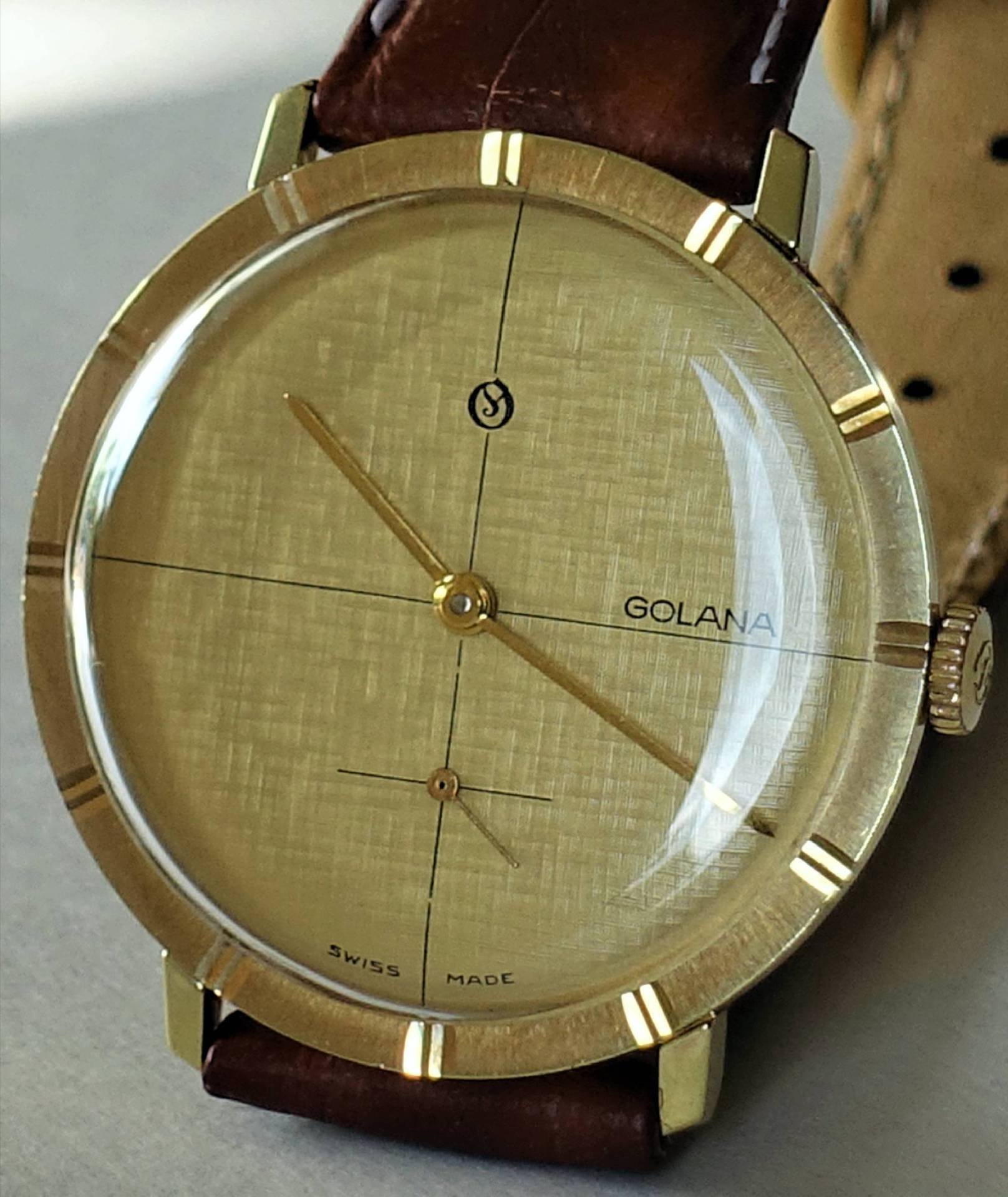 Goldfarbene Armbanduhr mit braunem Lederarmband und schlichtem Zifferblatt.