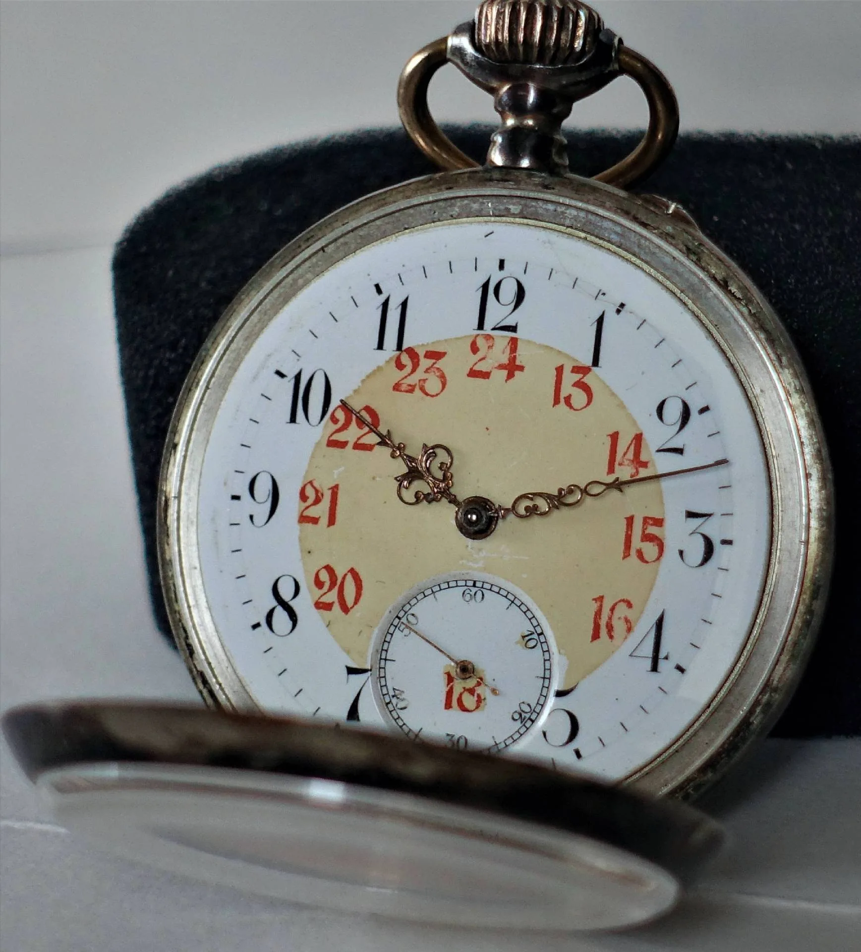 Silberfarbene Taschenuhr mit weißem Zifferblatt, schwarzen und roten Zahlen sowie filigranen Zeigern.