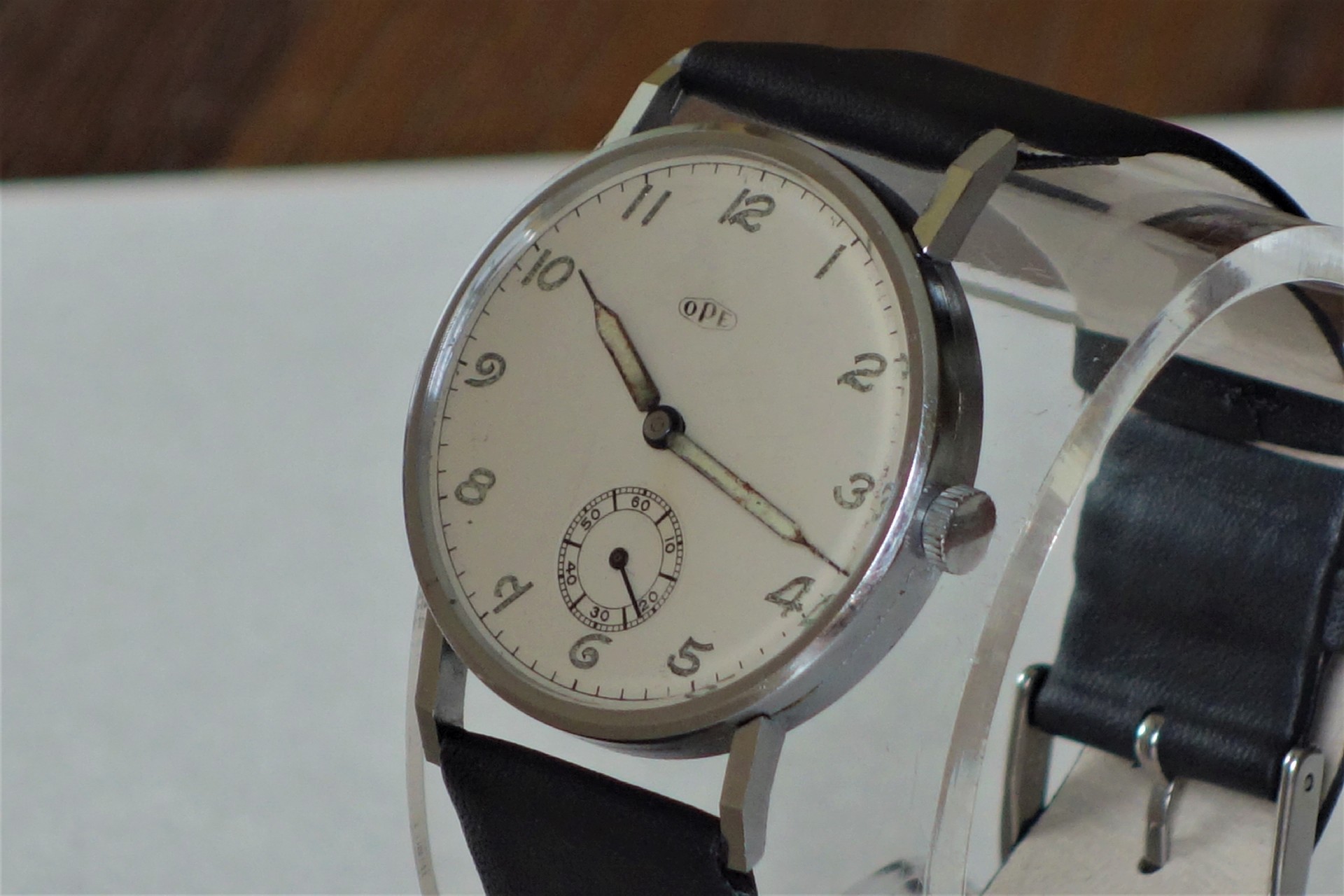 Silberne Armbanduhr mit weißem Zifferblatt und schwarzem Armband.