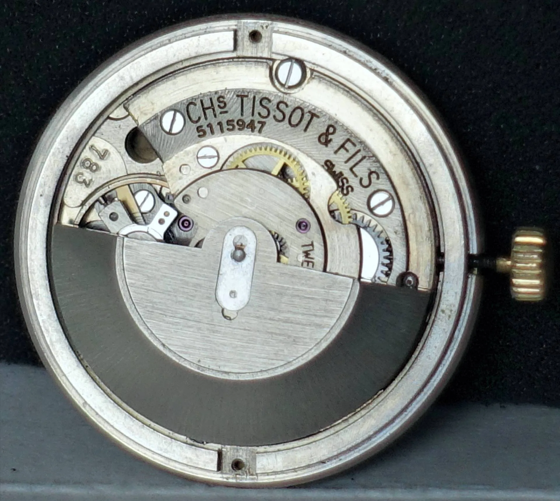 Silberfarbenes mechanisches Uhrwerk von Tissot mit sichtbaren Zahnrädern und Schwungmasse.