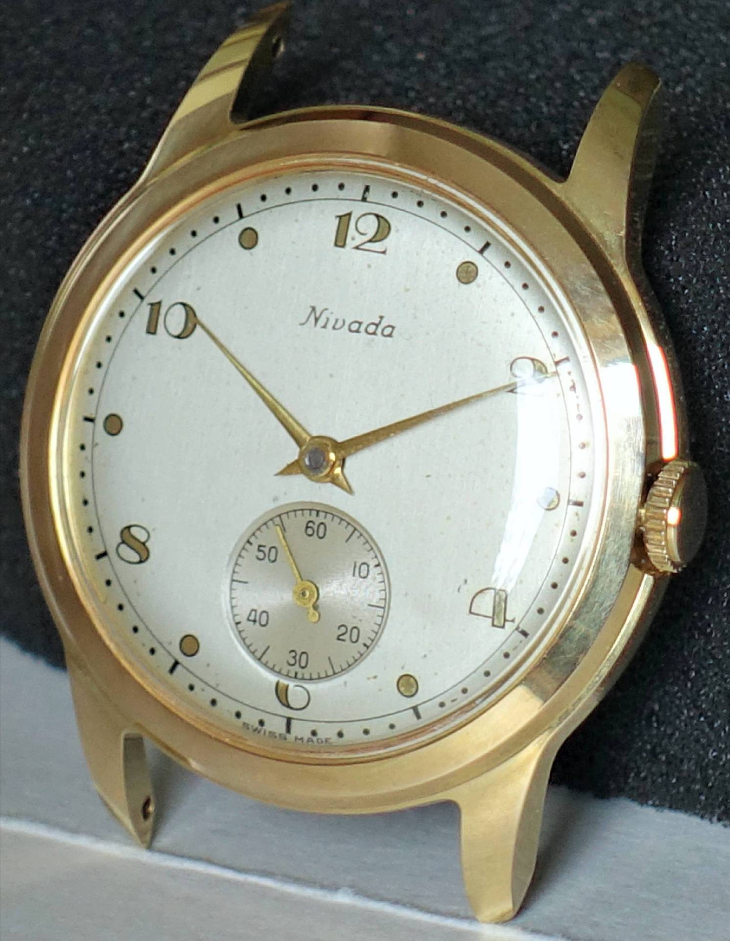 Goldfarbene Armbanduhr mit weißem Zifferblatt und kleiner Sekunde bei sechs Uhr.